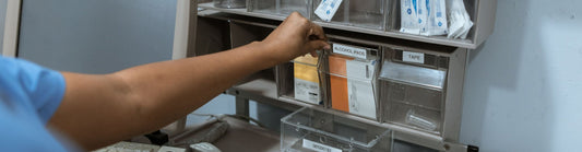 Clinician restocking labeled supply bins in a clinic storage room